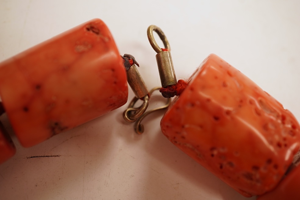 Two coral bead necklaces, one composed of large cylindrical coral beads, approximately 2.5-3.5cm each, total length 49cm; and a bracelet composed of carved coral beads spaced by smaller pink coral beads, on an elasticate